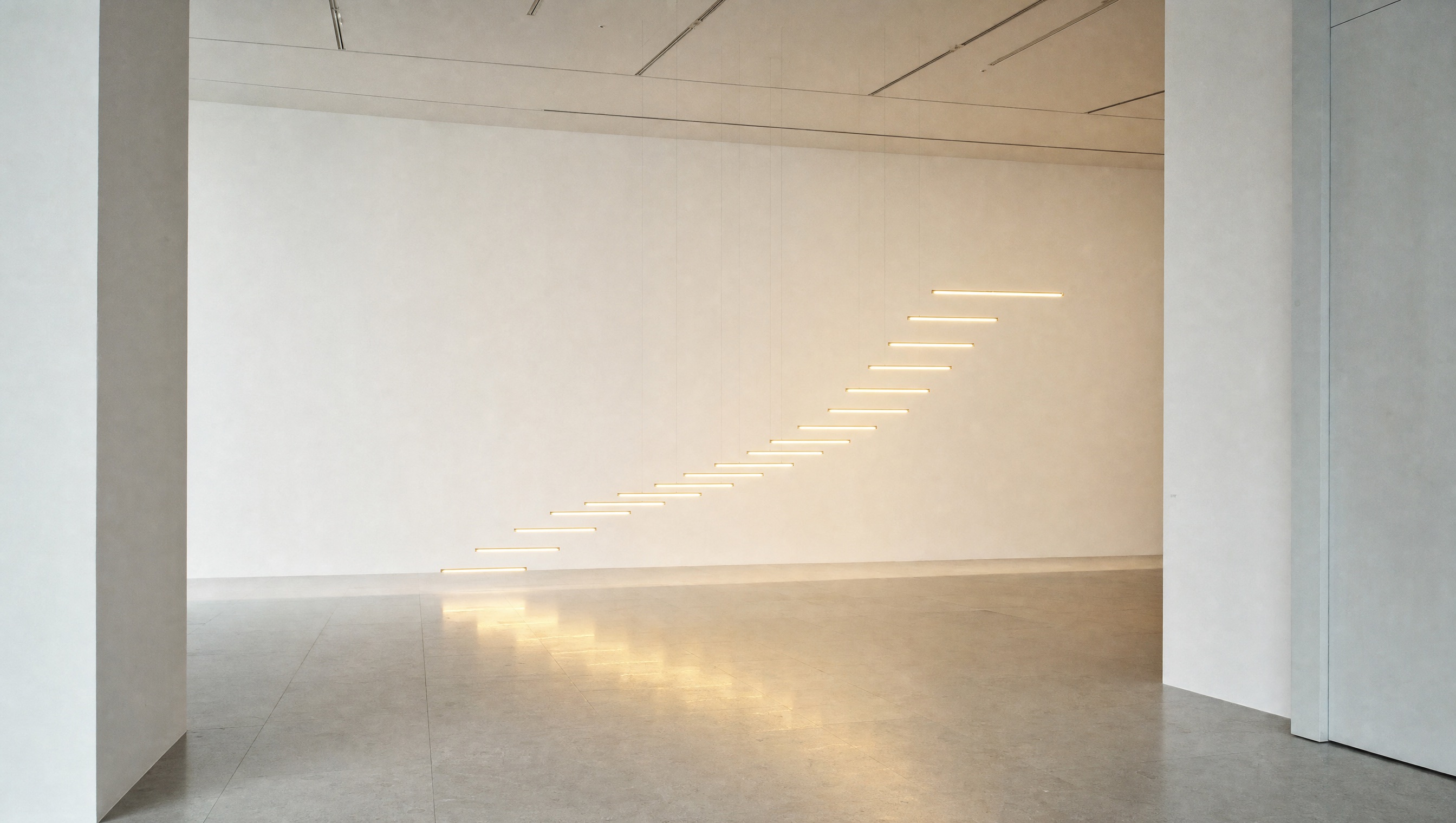 Thin bars of warm light rise gently from left to right in a bright gallery space, like a chart made of light.