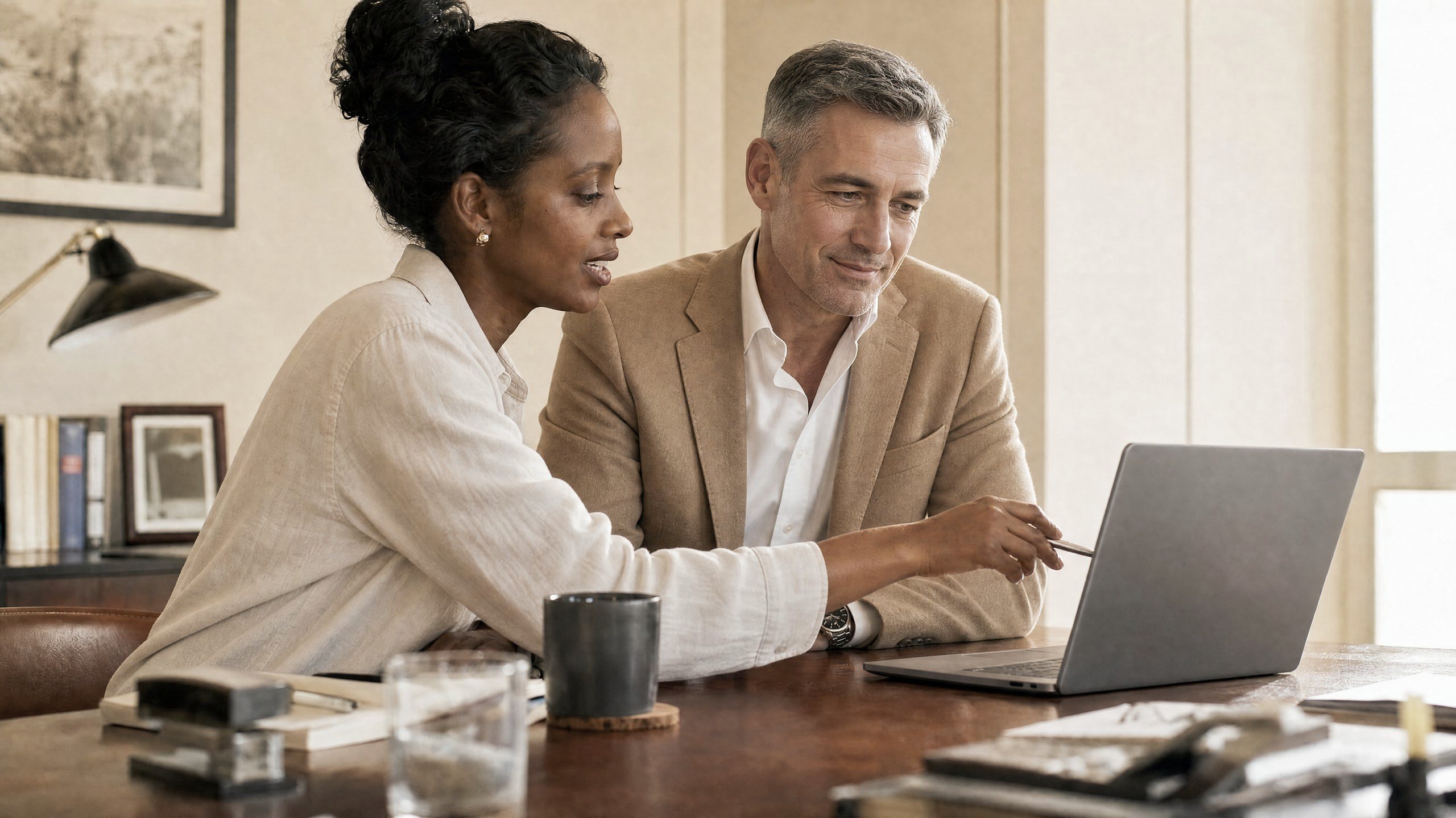 A Humanistics specialist beside a company leader at his own desk, showing him his platform on his laptop